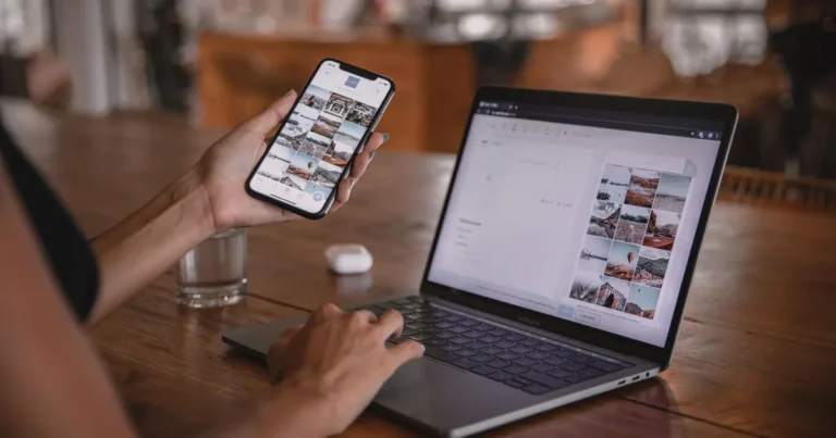 Rankos su telefonu ir nešiojamu kompiuteriu, kuriuose peržiūrimas socialinių tinklų turinys